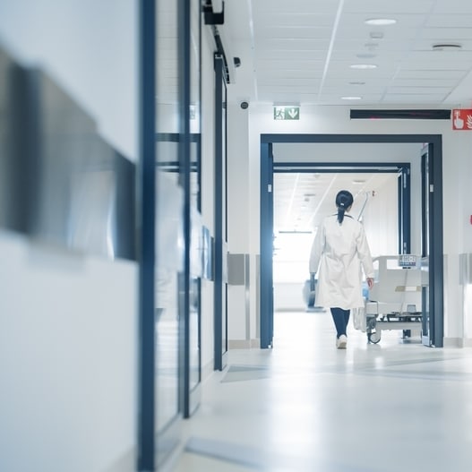 Couloir d'hôpital moderne avec professionnel de santé Professionnel de santé en blouse blanche marchant dans un couloir d'hôpital moderne et lumineux.